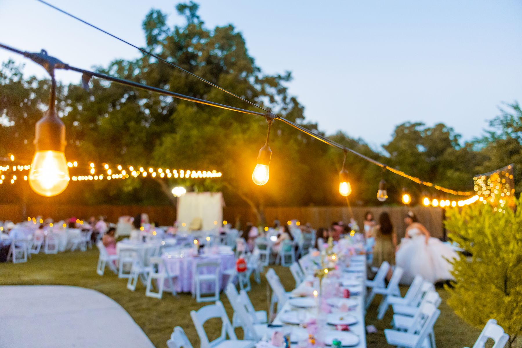 Open-air wedding reception with long tables beneath warm string lights